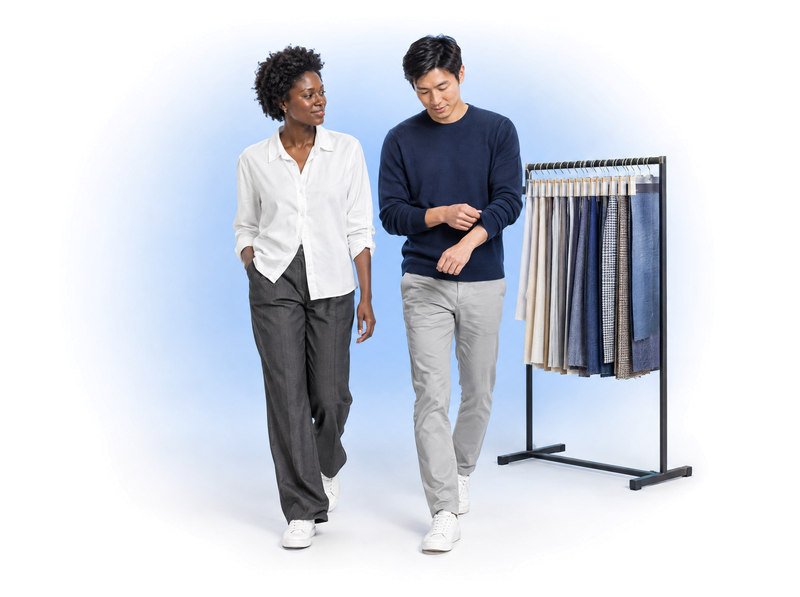 Two adults wearing everyday garments beside a rail of woven textile samples