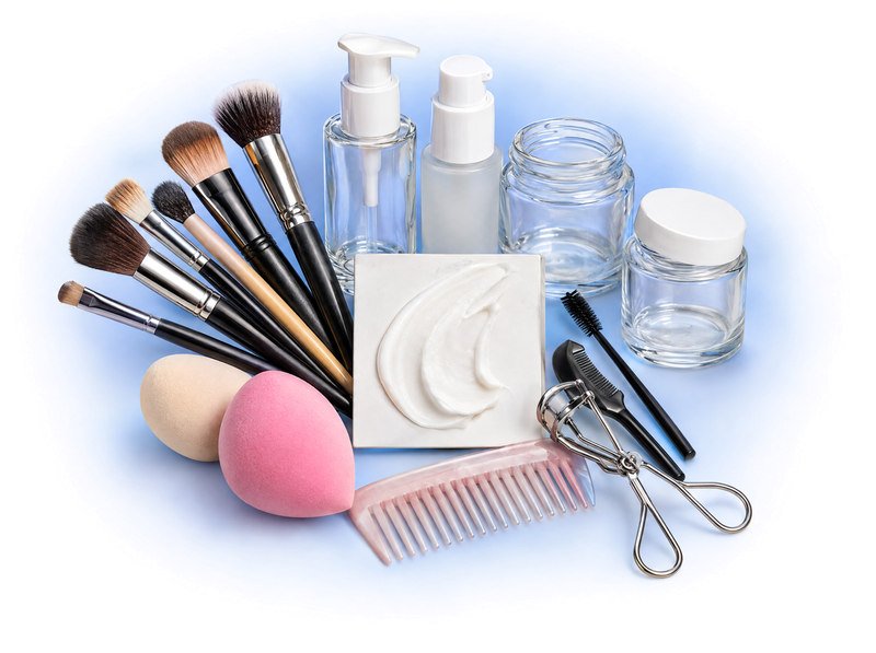 Cosmetic brushes, grooming tools, sponges and glass packaging arranged around a cream texture sample